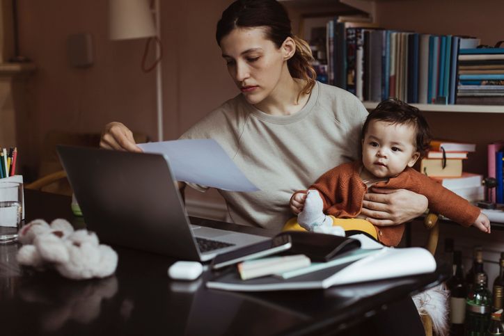 Female professional reading document while sitting with male toddler at home