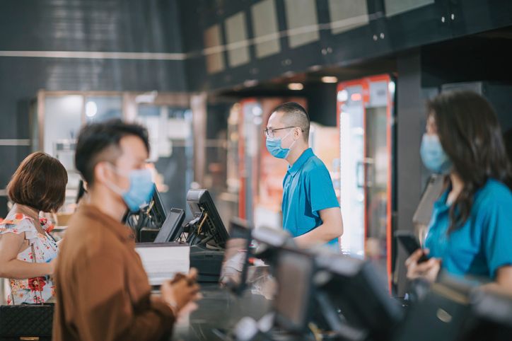 asian chinese customer with facemask buying movie tickets from cinema movie theater ticket counter
