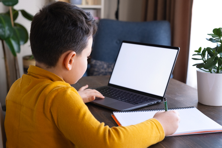 8-9 years cute child using laptop. Learning at home.