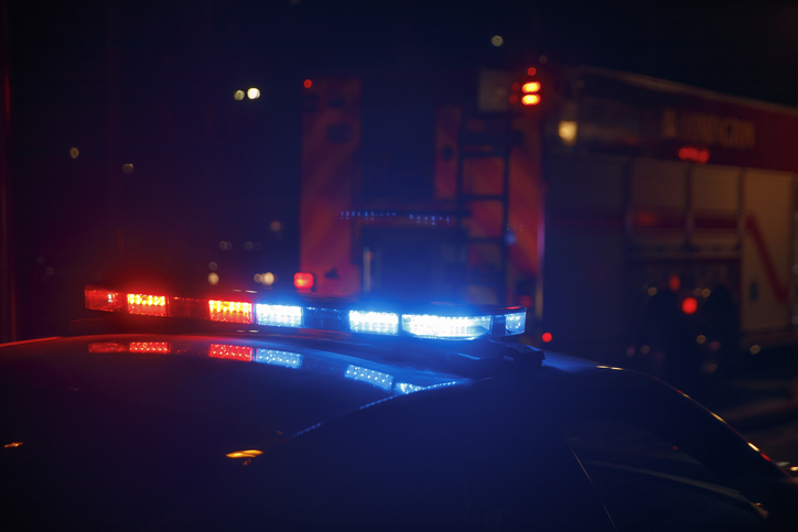 Emergency lights on a police car flash at the scene of a house fire