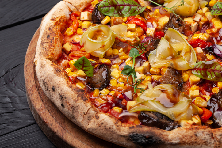 Italian or French pizza with different ingredients. Sausage, meat, cheese, tomatoes.