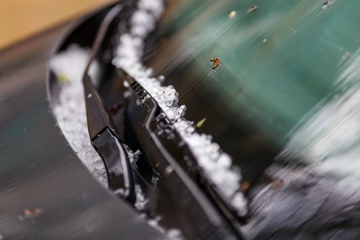 small hail ice balls on black car hood after heavy summer storm