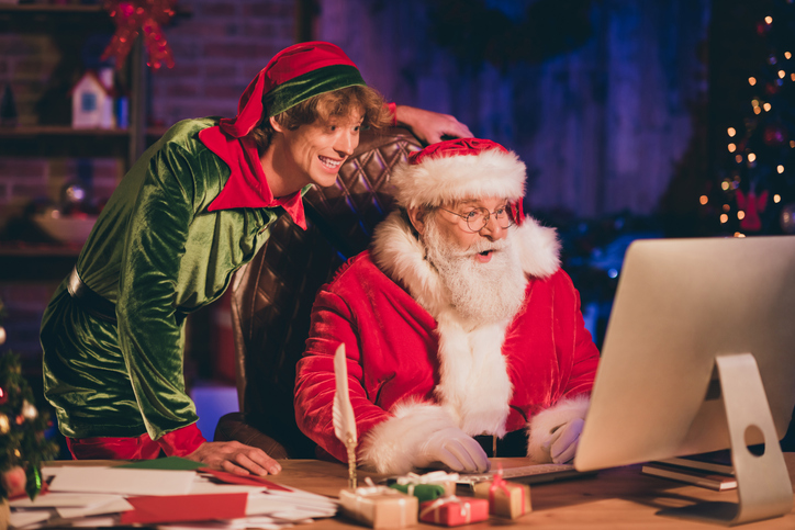 Photo portrait of santa claus and elf browsing internet on desktop