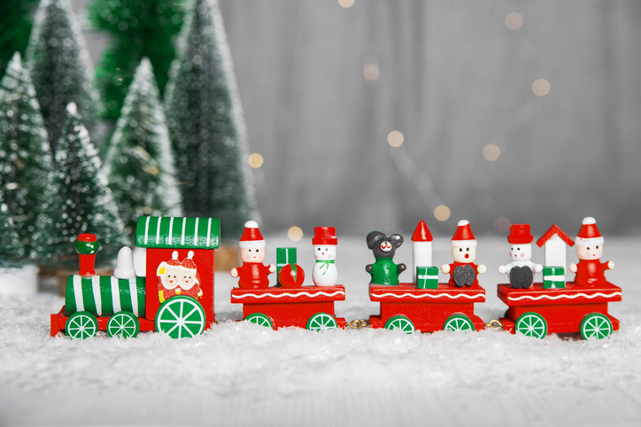 Merry Christmas and Happy New Year greeting card. Toy train with gifts and elves on background of Christmas trees.