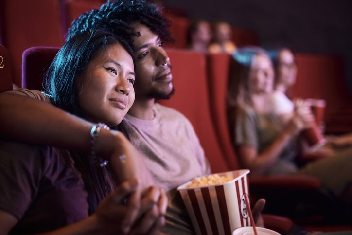 Embraced couple enjoying in a movie in theatre.