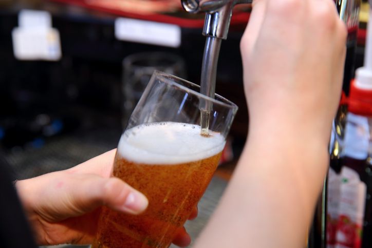 Pouring a Fresh and Refreshing Glass of Beer at the Bustling Bar with Friends Present