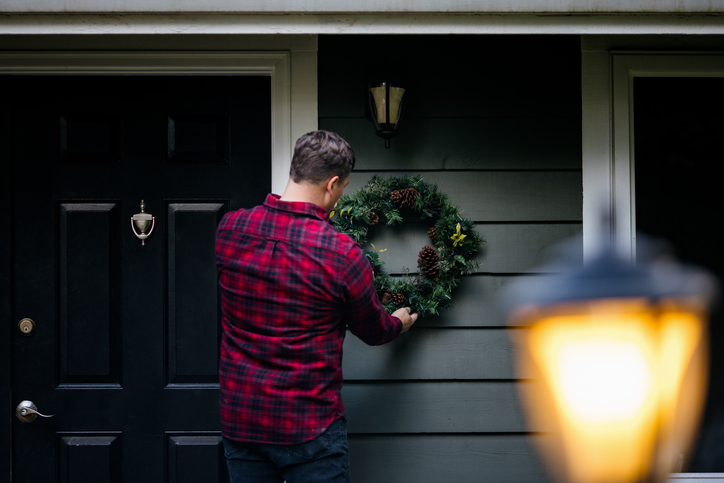 Man Decorating Home With Christmas Wreaths