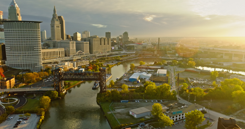 Drone Shot over Cuyahoga River with Downtown Cleveland on Left at Sunrise
