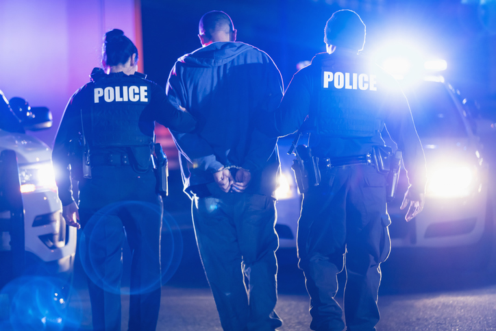 Handcuffed suspect being arrested by police at night
