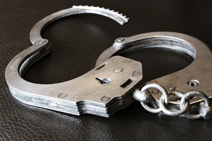 A closeup view of handcuffs placed against a dark background for better visibility and emphasis