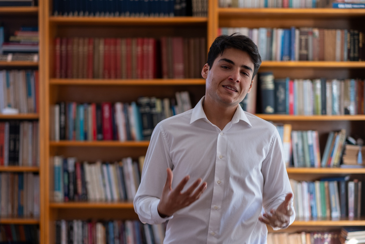 Young professor gesturing while explaining in university library