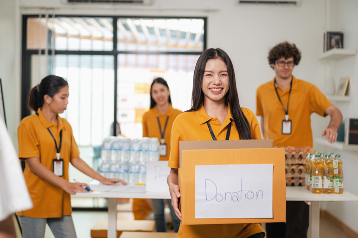 Portrait of volunteer holding donation box, group of volunteers helping to pack donations to be delivered to victims of natural disasters,