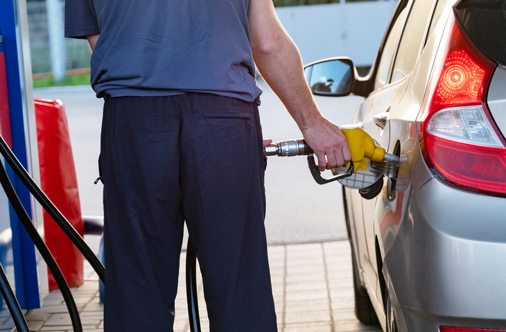 Fueling a car at a gas station during sunset light.