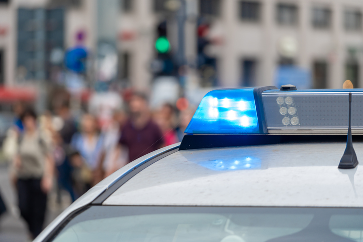 Close-up of blue flash light of a police car against people on a city street