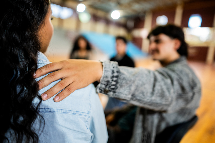 Close-up of man consoling person during group therapy