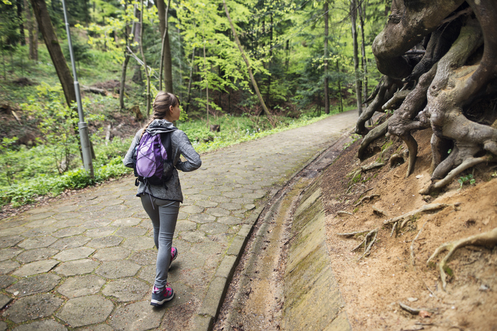 Little girl walking to school, through an old, weathered and bit mysterious public park