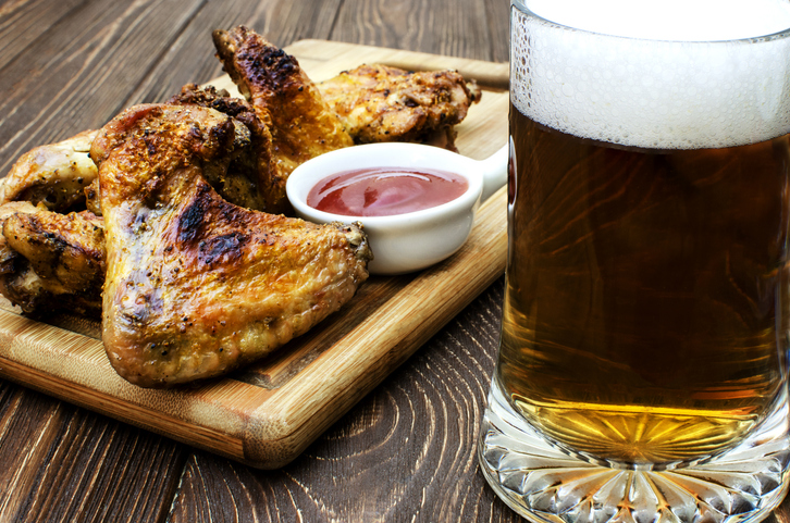Close-up of grilled chicken wings and beer in glass