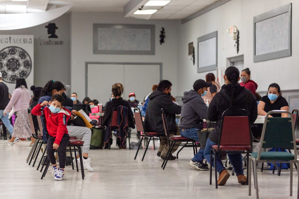 People wearing face masks wait in a line to finish the...