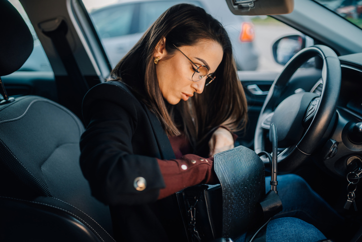 Businesswoman searching inside her handbag while sitting in car