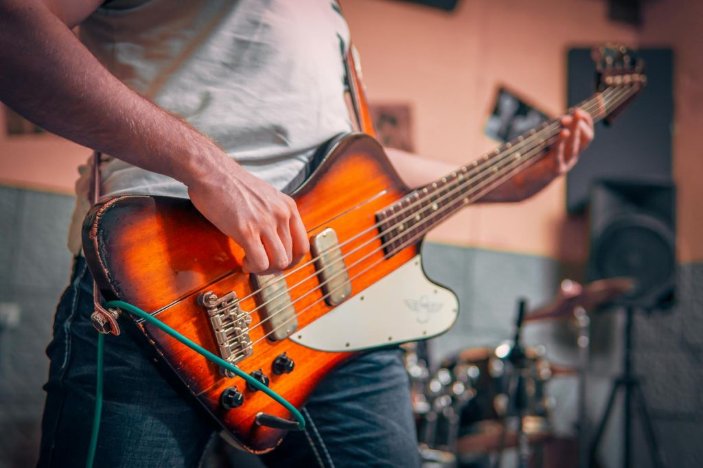 man in white t shirt playing brown electric guitar
