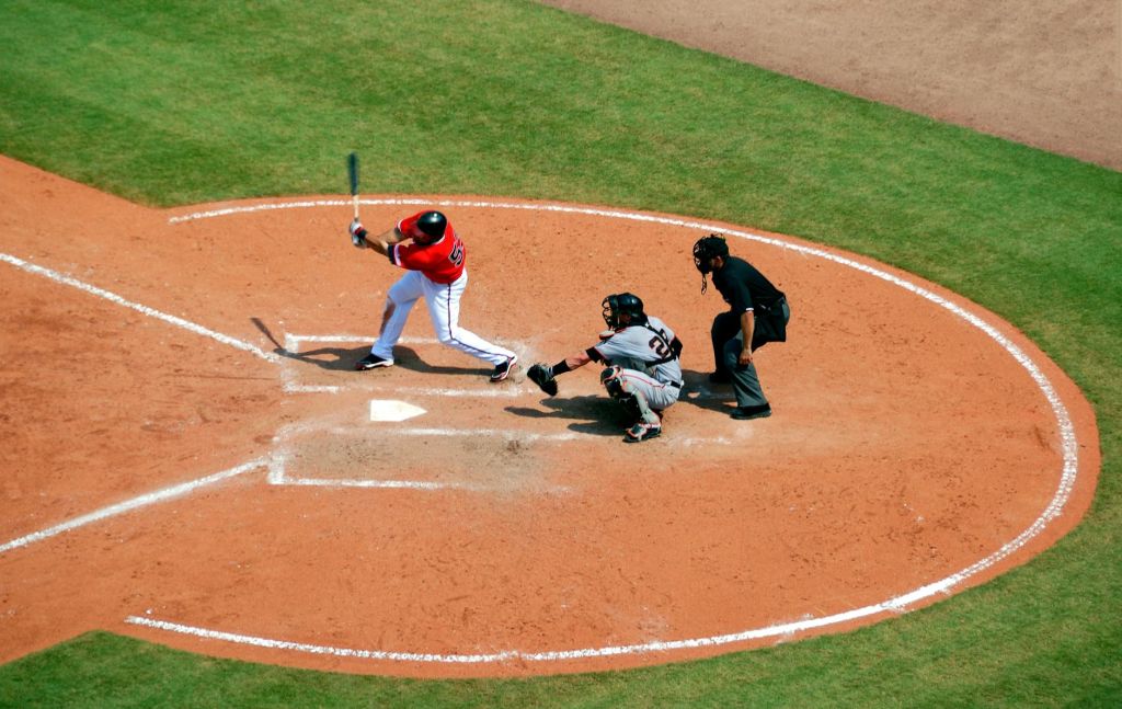 baseball player standing on baseball stadium with two men