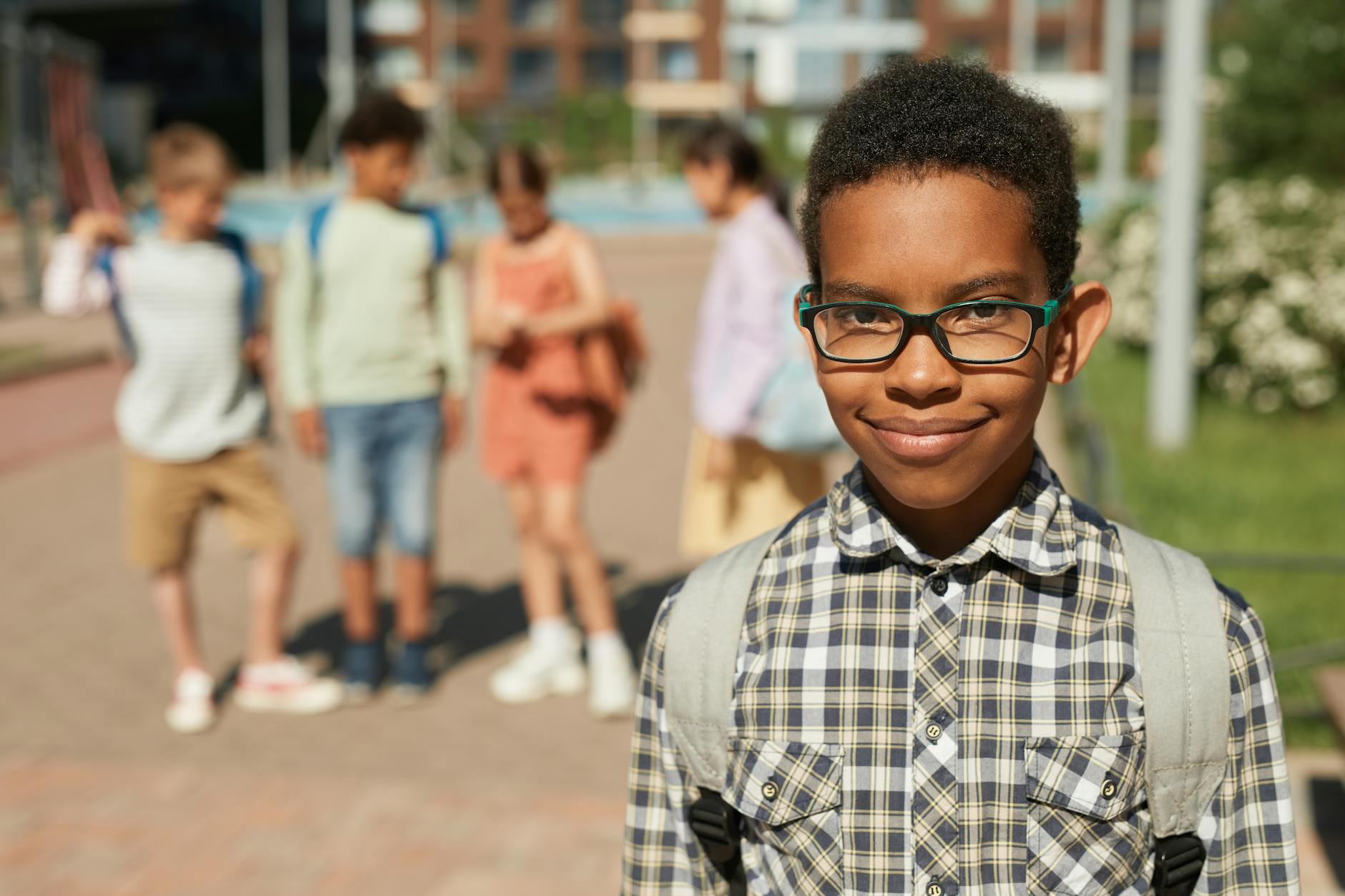 photo of a schoolboy in eyeglasses with a group of friends standing in the background