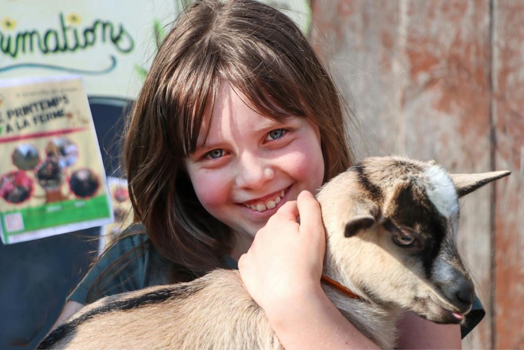 young girl joyfully holding a baby goat