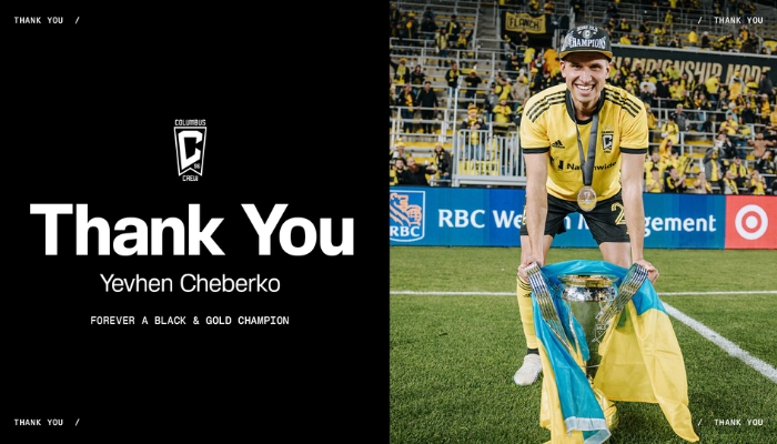 A soccer player in a yellow jersey celebrating with a trophy on a soccer field.