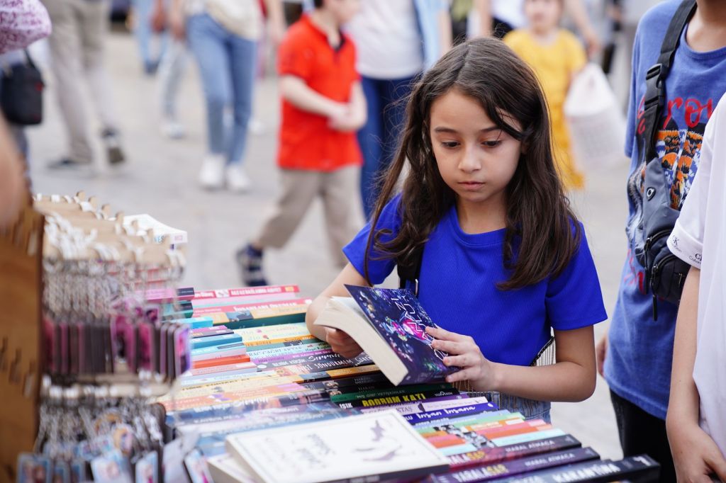 child reading book at outdoor market