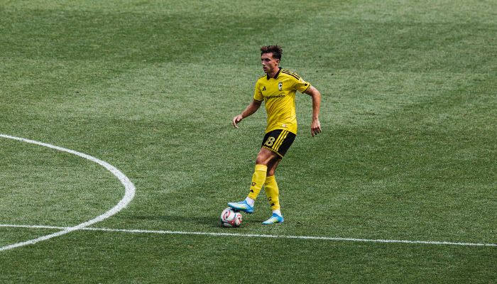 A soccer player in a yellow jersey dribbling a ball on a grassy field.