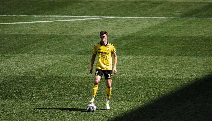 A soccer player in a yellow jersey dribbling a ball on a grassy field.