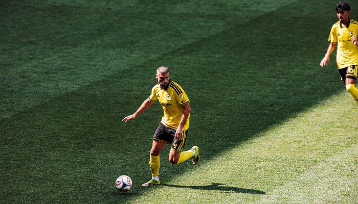 A soccer player in a yellow jersey dribbling the ball on a grassy field.
