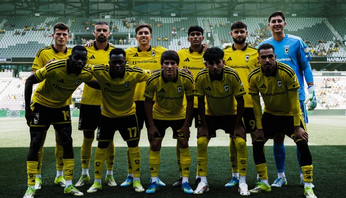 A group of soccer players in yellow uniforms posing for a team photo on a soccer field.