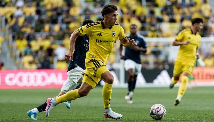 A soccer player in a yellow jersey dribbling the ball down the field during a match.