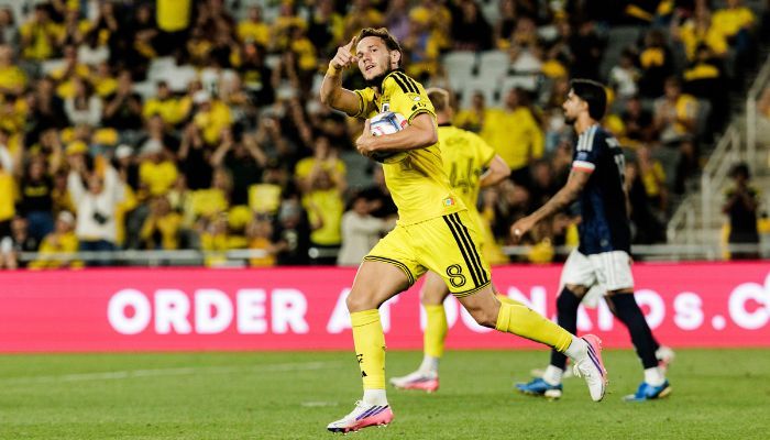 A soccer player in a yellow jersey celebrates after scoring a goal, with the "ORDER A 99s.C" text visible in the background.