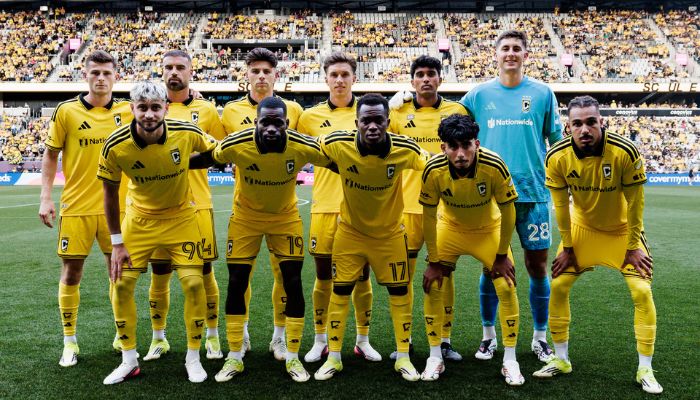 A soccer team in yellow uniforms posing for a group photo on a soccer field.