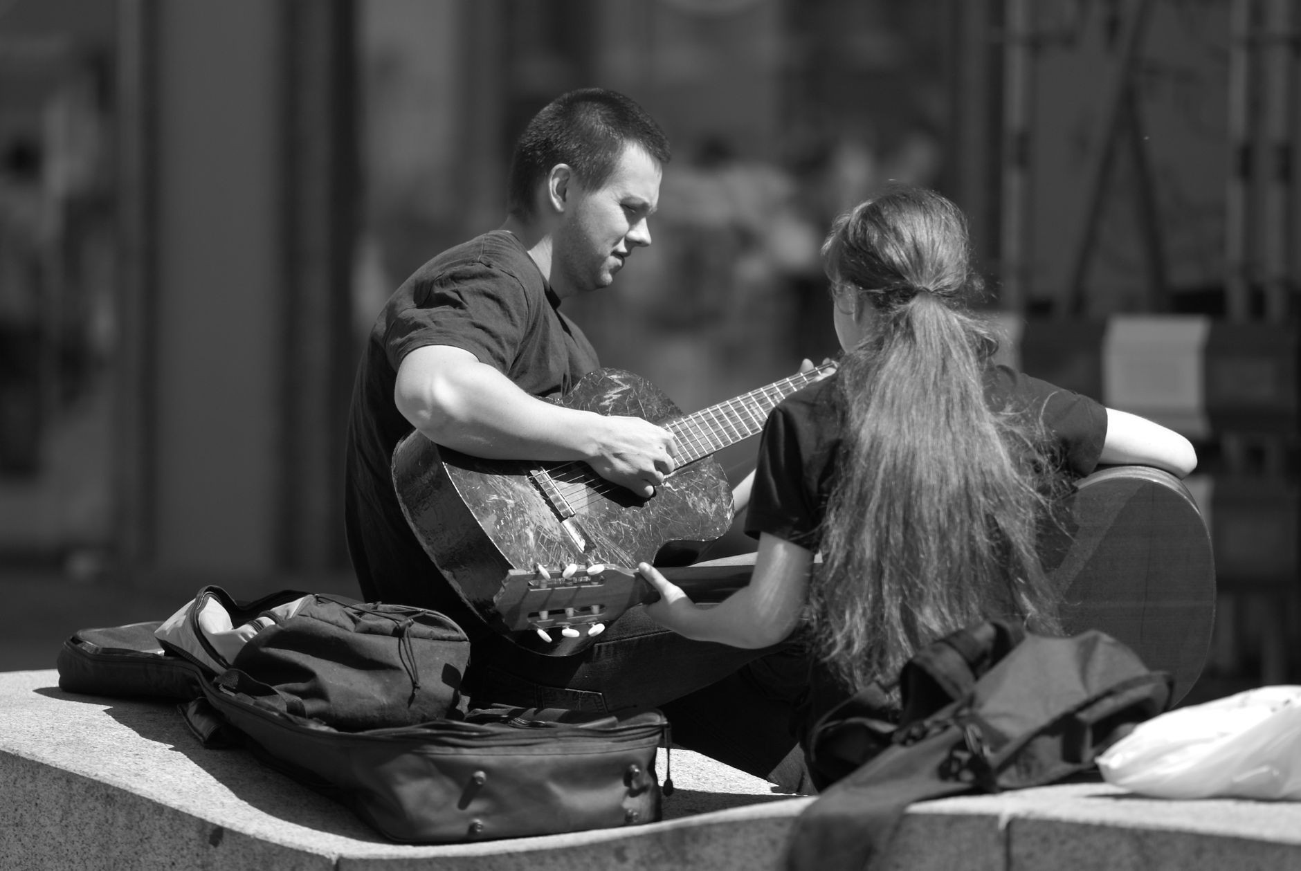 couple playing on a guitar on a street in black and white