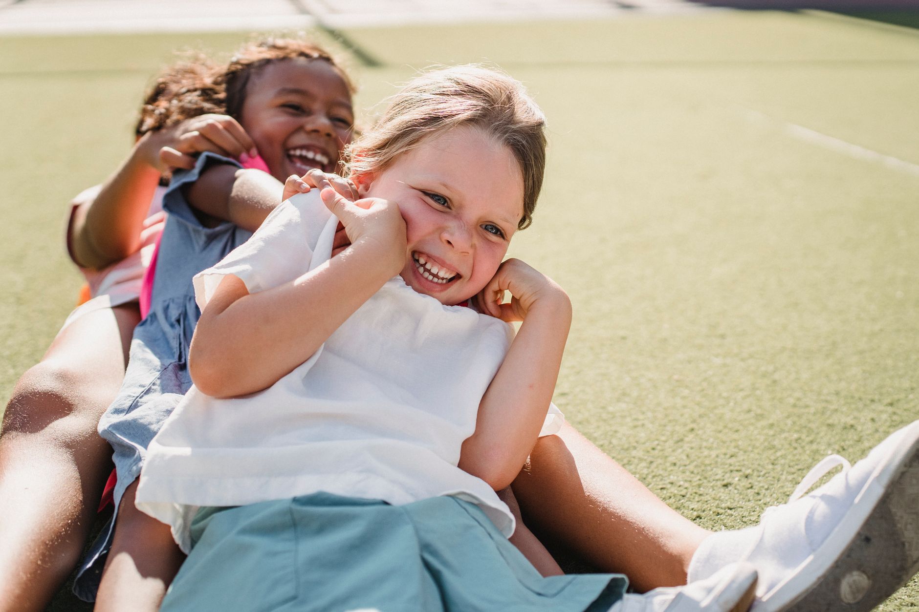 girl in white shirt smiling with hands on her cheeks