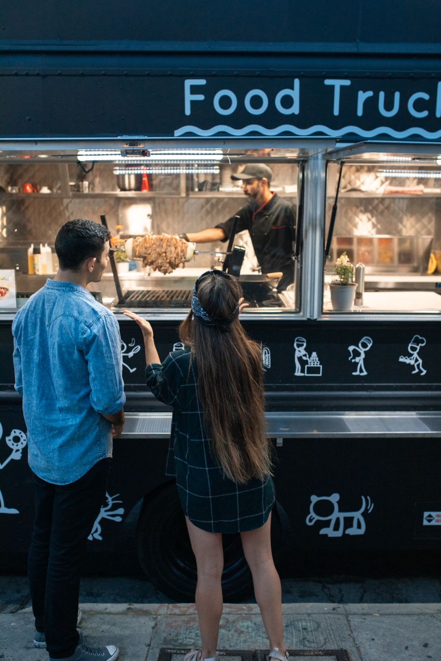man and woman standing in front of the food truck