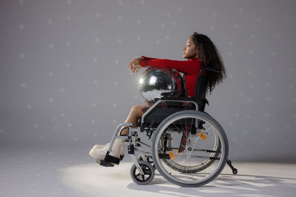 a young woman in a wheelchair holding a disco ball