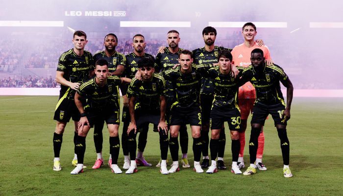 A soccer team in black and yellow uniforms posing for a group photo on a soccer field.