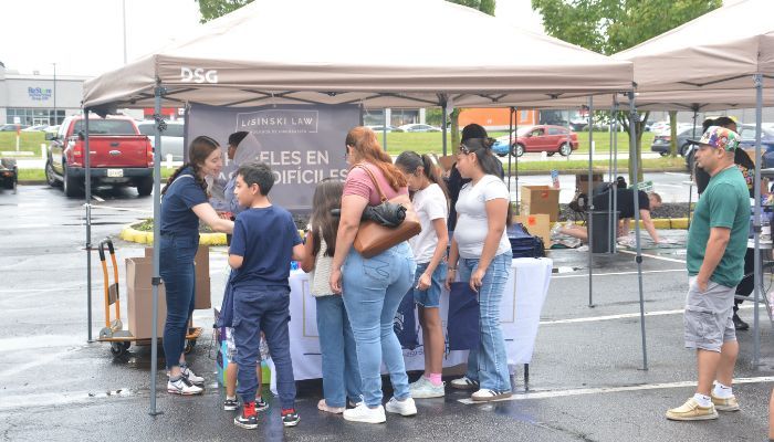 A group of people gathered under a tent at an outdoor event, with a "DSG" logo visible on the tent.
