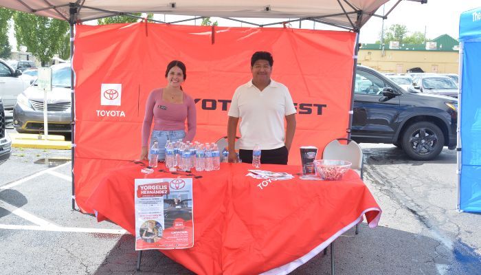 Two people staffing a Toyota booth at an event, with Toyota branding and promotional materials visible.