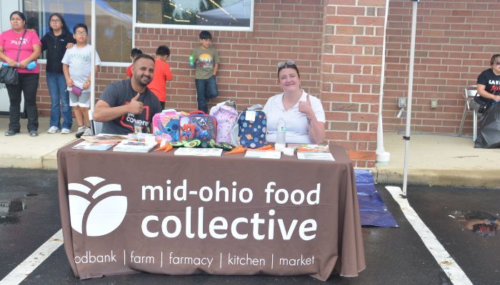 A group of people staffing a booth for the Mid-Ohio Food Collective, which provides food bank, farm, farmacy, kitchen, and market services.