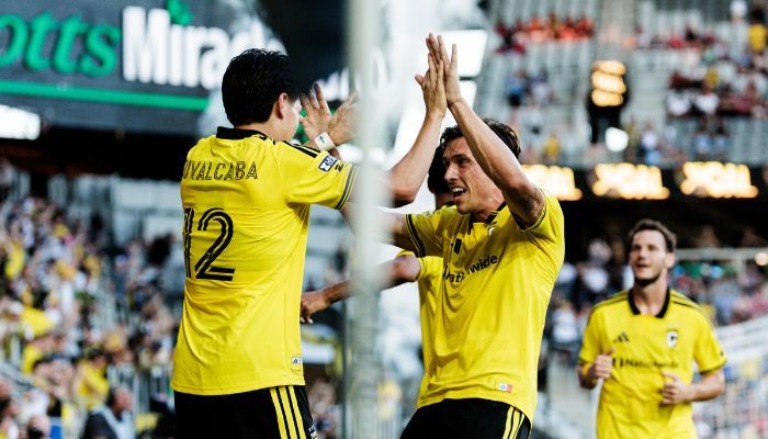 Two soccer players in yellow jerseys celebrating a goal, with one player raising his arms in excitement.