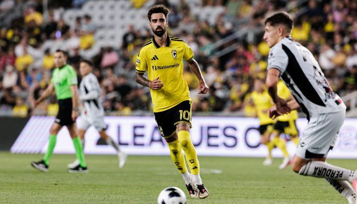 A soccer player in a yellow jersey dribbling the ball on a soccer field.