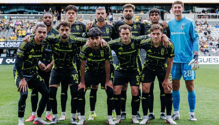 A soccer team in black and yellow uniforms posing for a group photo on a soccer field.