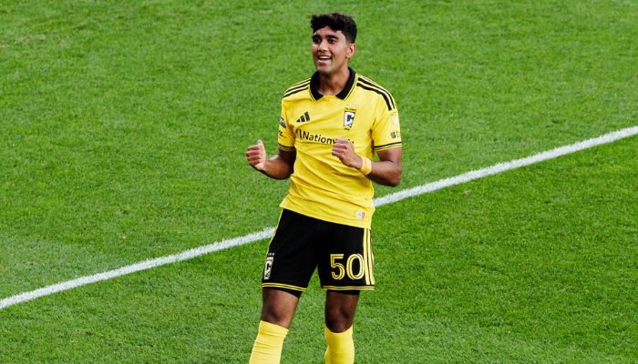A soccer player in a yellow jersey with the number 50 on the back, running on a green field and celebrating.