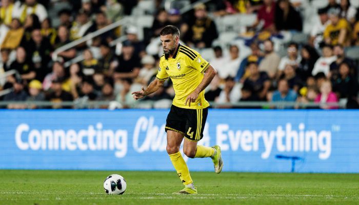 A soccer player in a yellow jersey dribbling a ball on a field, with the text "Connecting Everything" visible in the background.