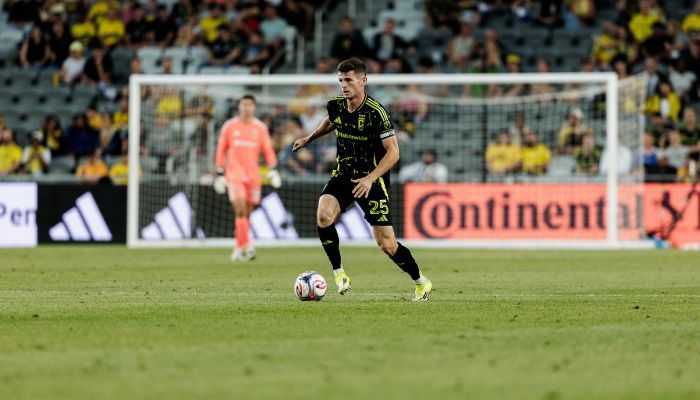 A soccer player in a yellow jersey dribbling the ball on a soccer field during a game.